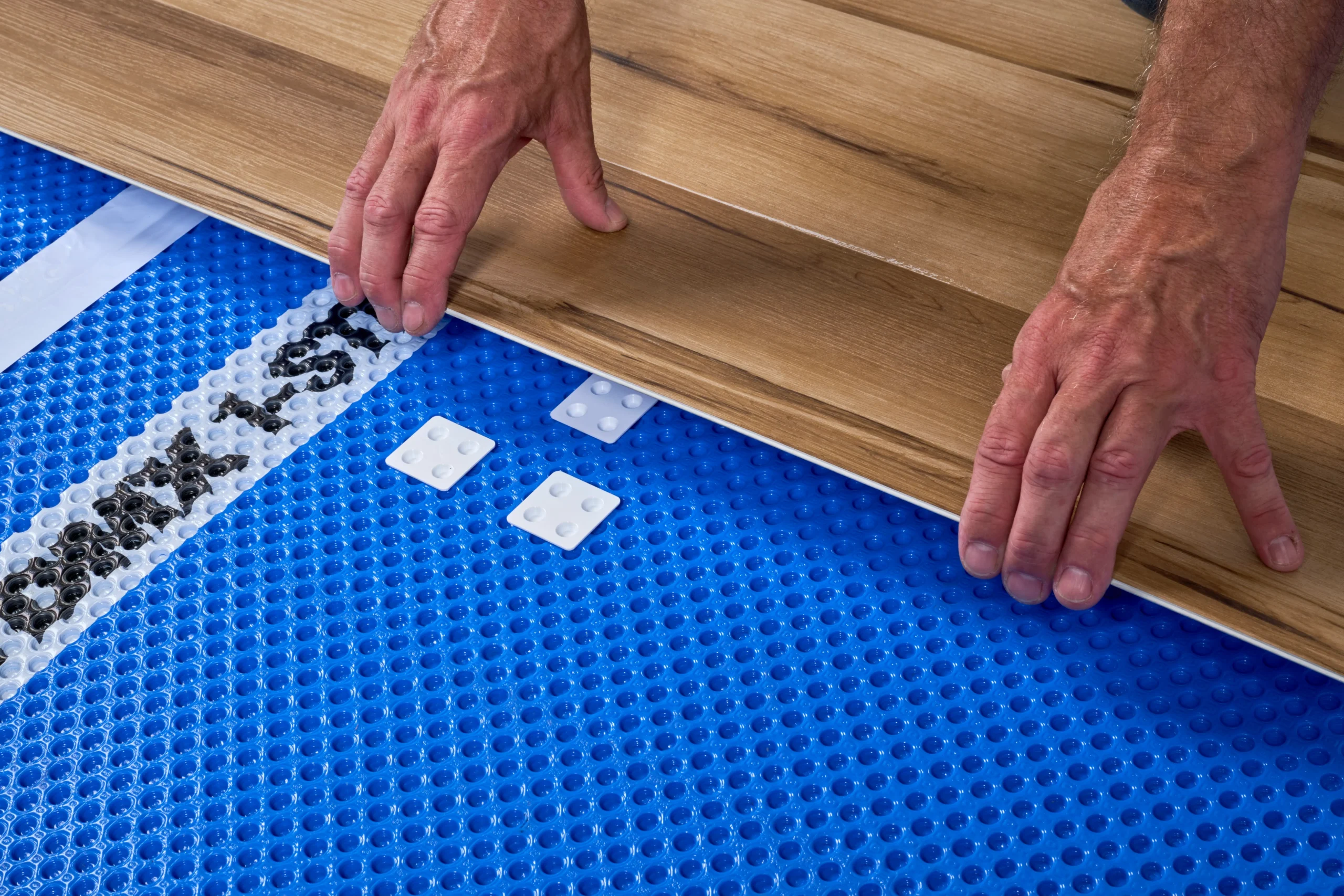 Installation of DMX 1-Step 2.0 under vinyl plank flooring, showcasing the use of the included DMX Easy Shims
